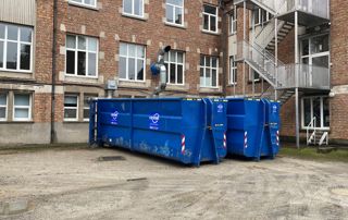 containers bleus devant un immeuble