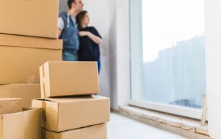 Piles de cartons avec couple devant une fenêtre