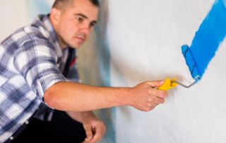 peintre appliquant de la peinture bleue au rouleau